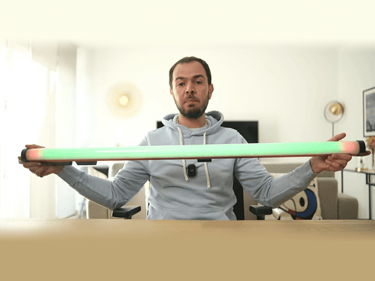 A content creator holding the 1.2-meter GVM-BD45R wand light with a vibrant green and pink gradient, showcasing the ultimate Video Wand Light for elevating your led light stick photography and YouTube studio setup.